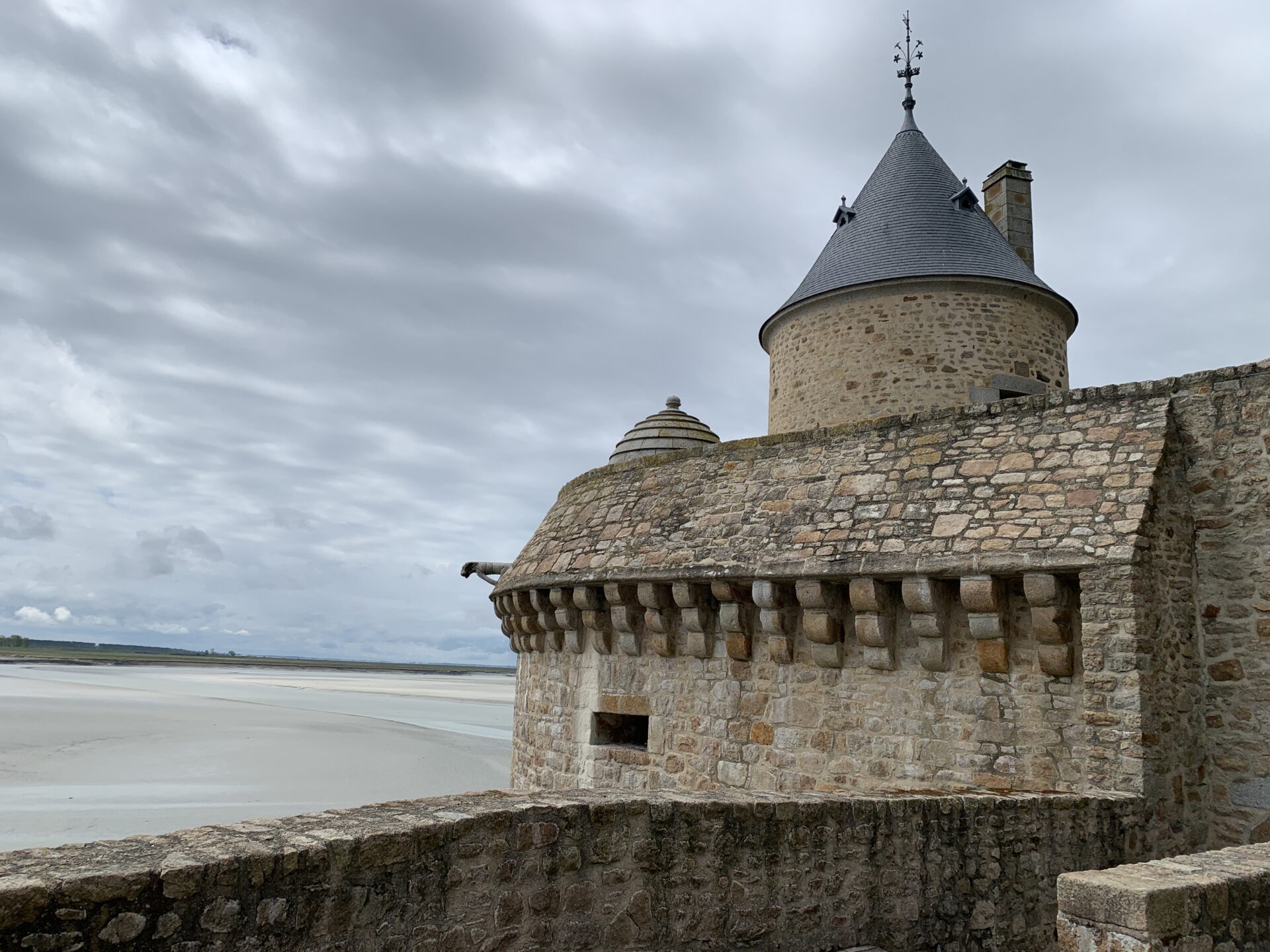 Photo de l'intérieur des remparts en pierre du Mont-Saint-Michel avec sur sur le sable qui l'entoure