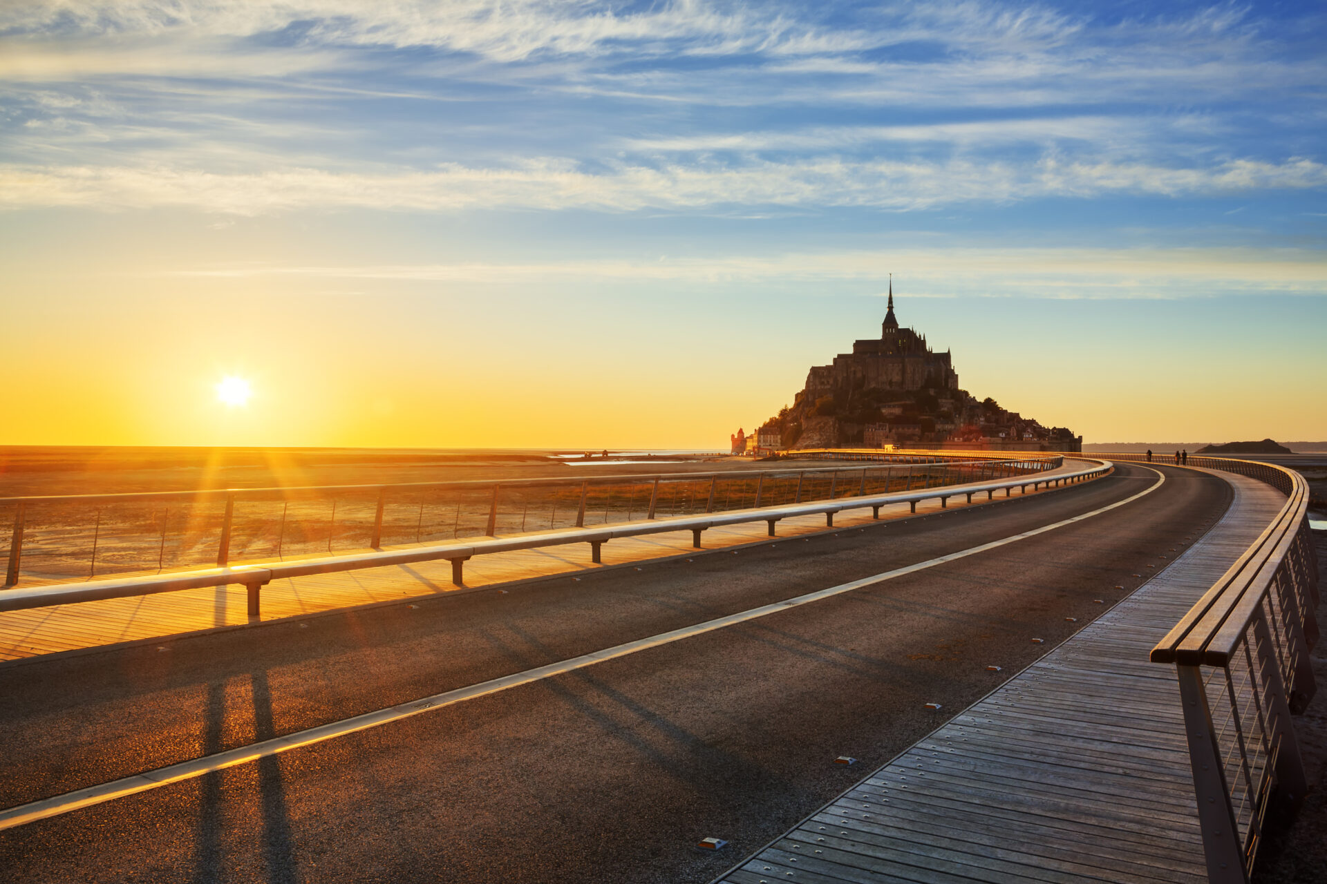 Route allant vers le Mont-Saint-Michel avec coucher de soleil sur le côté sur la plage
